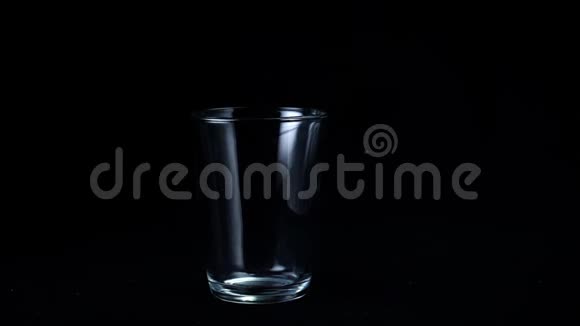 透明玻璃杯上黑色隔离背景框架茶座上的玻璃从微弱的白光中闪烁出来视频的预览图