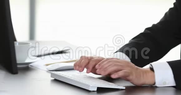 在现代办公室的电脑前关闭商人在电脑键盘上打字的场景视频视频的预览图
