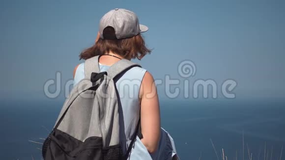 一位美丽的年轻旅游女孩的肖像看着灯塔背着背包戴着草帽视频的预览图