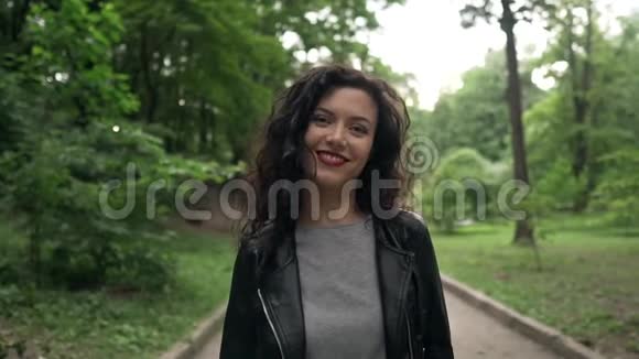 年轻美丽的卷曲的深色头发的女性微笑着行走视频的预览图