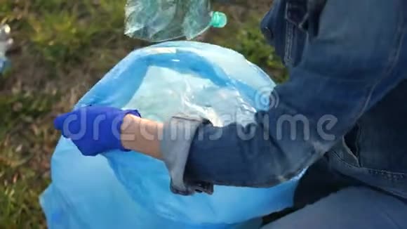 特写一个志愿者手收集垃圾的蓝色大塑料袋废物分类环境概念视频的预览图