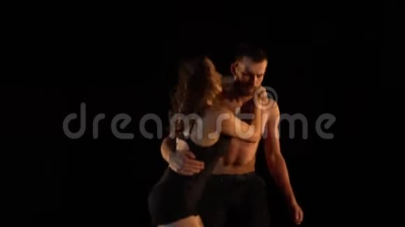 一个长着胡子的男人和一个深褐色皮肤的女人在黑暗中缓慢地练习杂技瑜伽视频的预览图