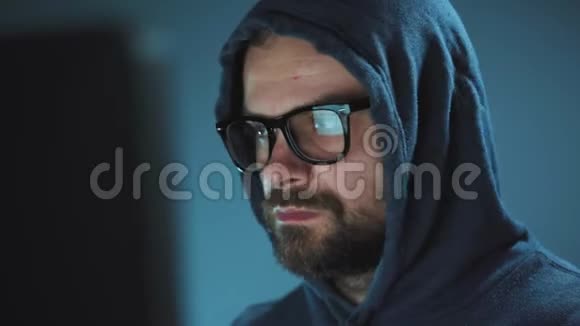 戴着头巾的男黑客和戴着眼镜在黑暗的办公室里用电脑工作网络犯罪概念视频的预览图