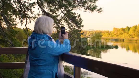 两位资深女性在秋季公园打电话拍摄河流视频的预览图