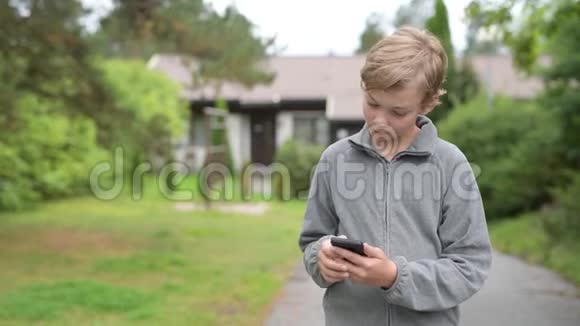 小男孩在户外用手机和自拍视频的预览图