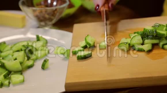 一个拿着刀的女人把切片的黄瓜放在白色的盘子里视频的预览图