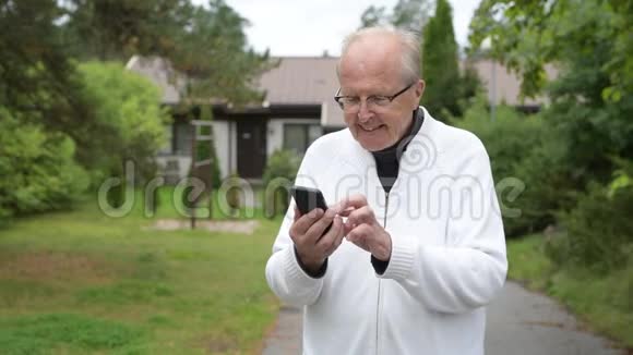快乐的老人在户外使用电话时微笑视频的预览图