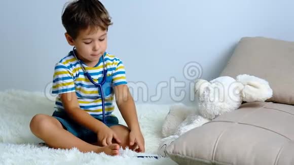 慢动作小男孩扮演医生孩子对待他的玩具兔子医生和病人医药和保健视频的预览图