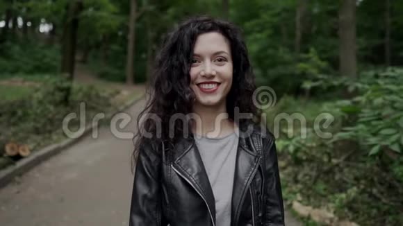 年轻美丽的卷曲的深色头发的女性微笑着行走视频的预览图