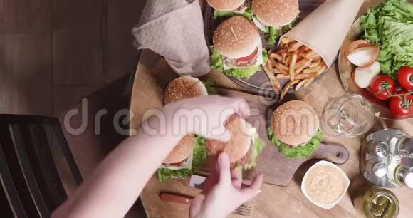 用汉堡和厨师的双手将其放在桌上的俯视构图视频的预览图