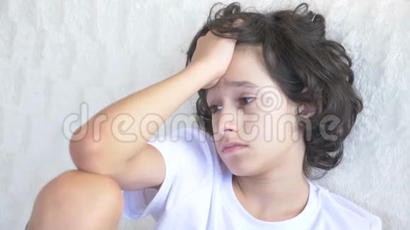 一个悲伤疲惫的少年坐在沙发上的肖像4k视频的预览图