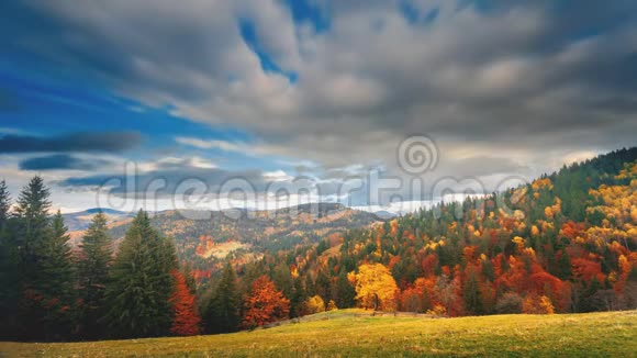 灰色的云彩漂浮在覆盖着山丘的彩色混交林上视频的预览图