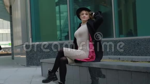 戴帽子的女士摆姿势坐在长凳上看起来向上视频的预览图