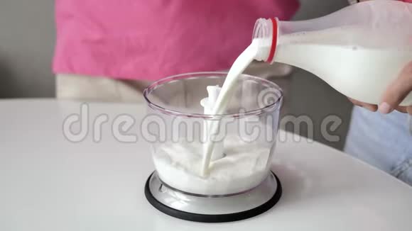特写雌性的手把牛奶从瓶子里倒入透明的杯子里作为搅拌机视频的预览图