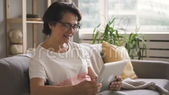 戴眼镜的老妇人微笑着享受视频通话视频的预览图