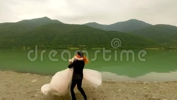 浪漫的约会新娘和新郎在河边背景是风景如画的山脉视频的预览图