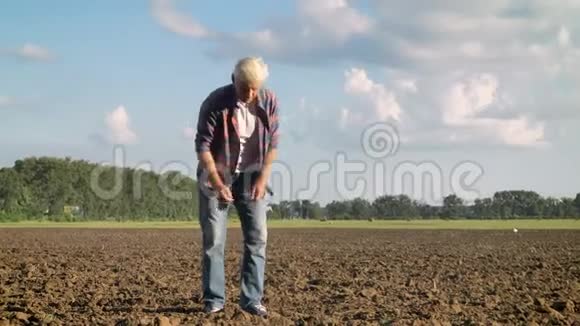 在炎热的夏日里老农坐在田里一手抓土视频的预览图