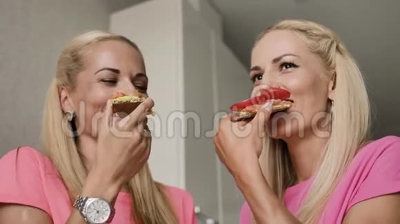 两个金发女郎吃一个红鱼三明治和一个西红柿烤面包视频的预览图