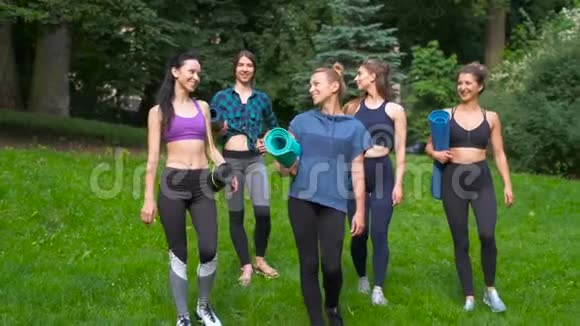 一群活跃的五个微笑的女性去锻炼夏天早上在公园拿着瑜伽垫积极的生活方式视频的预览图