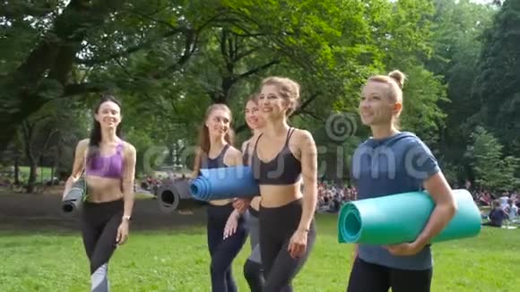 一群活跃的五个微笑的女性去锻炼夏天早上在公园拿着瑜伽垫积极的生活方式视频的预览图