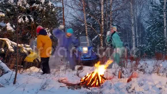 冬季森林一个年轻的家庭在火边的树林里打雪球视频的预览图