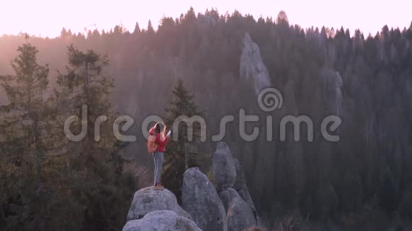 女人坐在悬崖边的森林背景下视频的预览图