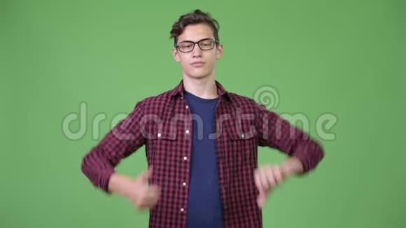 年轻英俊的书呆子男孩在竖起大拇指和放下大拇指之间选择视频的预览图