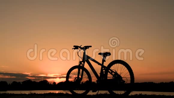 一辆孤独的自行车站在水边黎明时分一个少年走近自行车骑在自行车上视频的预览图