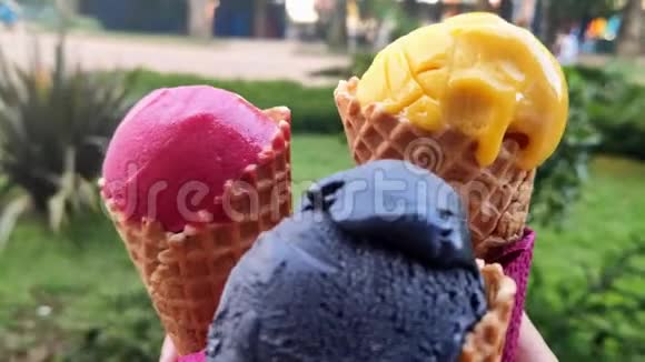 食物概念特写镜头有人握着他的手在相机上展示了三种五颜六色的冰淇淋非常适合视频的预览图