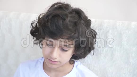 一个悲伤疲惫的少年坐在沙发上的肖像4k视频的预览图