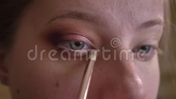 年轻的白种人女化妆师用刷子涂白眼影的特写照片视频的预览图