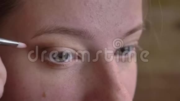 年轻的白种人女化妆师用刷子涂棕色眼影的特写肖像视频的预览图