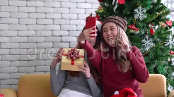 亚洲女性在圣诞假期用手机展示礼物和自拍视频的预览图