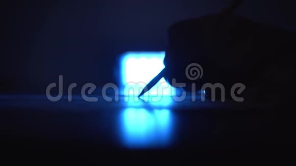 男人在房间里的一张纸上写字一只雄性手在深蓝色的光线下写在纸上视频的预览图