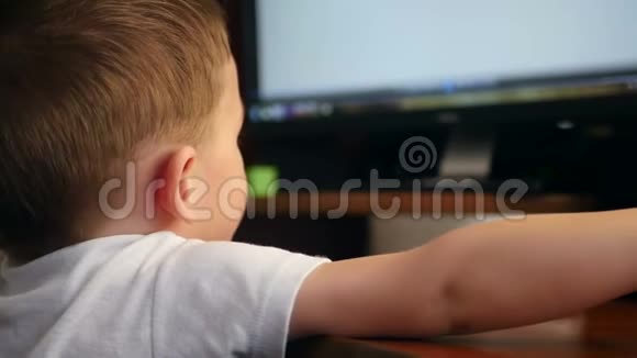 孩子正坐在电脑前玩游戏孩子用鼠标控制电脑视频的预览图