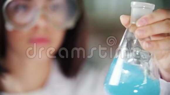 化学实验室的年轻女子拿着一瓶液体摇了摇把注意力集中在烧瓶上视频的预览图