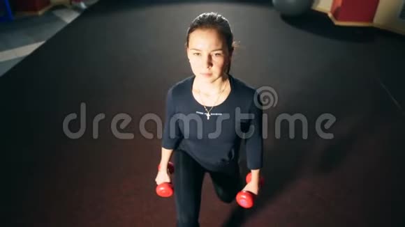 健身房里的女孩用哑铃做午餐锻炼大腿和臀部的肌肉视频的预览图