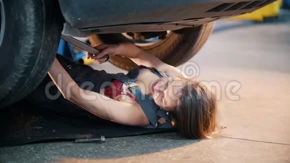 机械师女孩躺在车下伸手抓住扳手燃烧的雪花慢动作视频的预览图