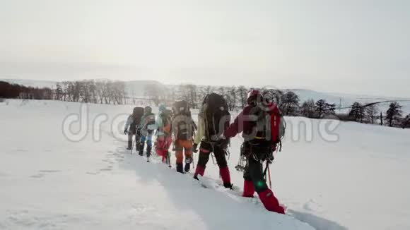 一群登山者自信地穿过最深的漂流排成一行在他们背后沉重的背包和视频的预览图