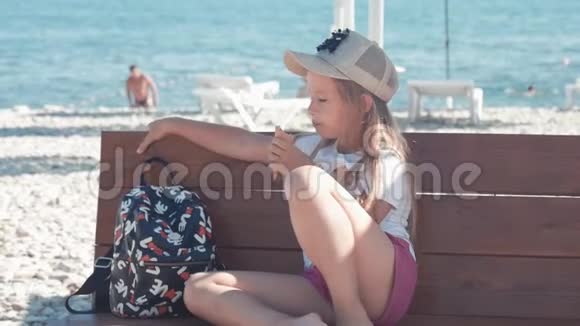 十几岁的女孩在暑假谈论坐在海边的长凳上吃冰淇淋孩子们在海滩上吃冰淇淋视频的预览图