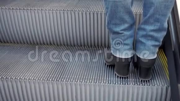 女人穿着靴子和牛仔裤腿走上扶梯视频的预览图