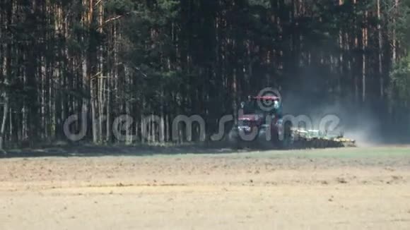 拖拉机红柄尘土飞扬的棕壤圆盘耙在针叶林的背景上视频的预览图
