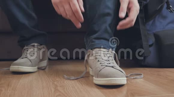 一个男人坐在沙发上把鞋带系在鞋子上旁边是一个旅游背包视频的预览图