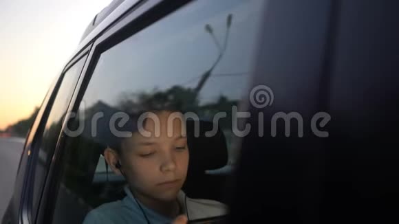 带着耳机在车里看智能手机电影的青少年视频的预览图