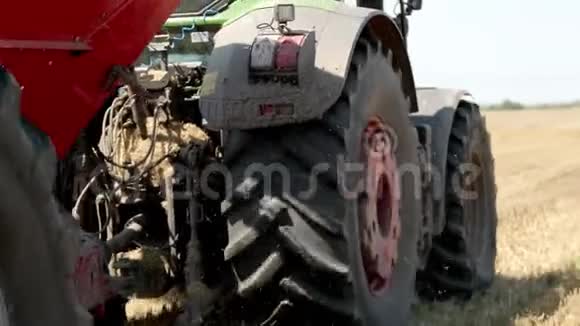 绿色拖拉机与一个红粮槽在田野上行驶在收获道具慢动作视频的预览图