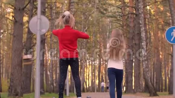 快乐的少年女孩走在秋天的公园里骑在陀螺仪上视频的预览图