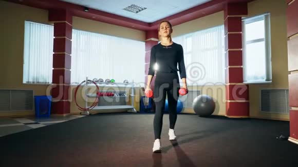 健身房里的女孩用哑铃做午餐锻炼大腿和臀部的肌肉视频的预览图