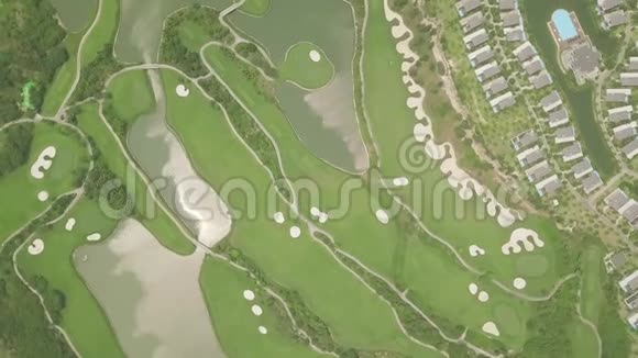 绿色高尔夫球场与湖在豪华别墅村空中景观从无人驾驶高尔夫俱乐部俯瞰绿野视频的预览图