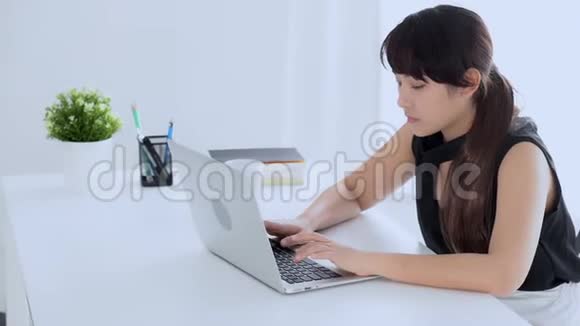 美丽的年轻自由职业亚洲女性在办公室打哈欠时工作在笔记本电脑上喝咖啡视频的预览图