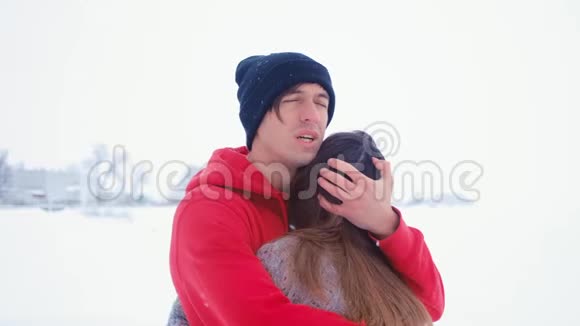 年轻悲伤的男人拥抱他的妻子感情上的一对情侣在冬天的雪地里拥抱视频的预览图